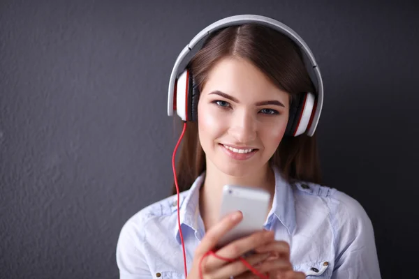 Ragazza sorridente con le cuffie seduto sul pavimento vicino al muro — Foto Stock