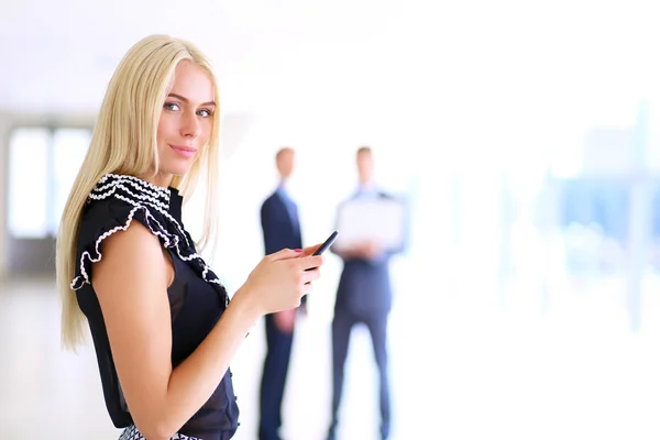 Hermosa mujer de negocios usando el teléfono celular, de pie en la oficina —  Fotos de Stock