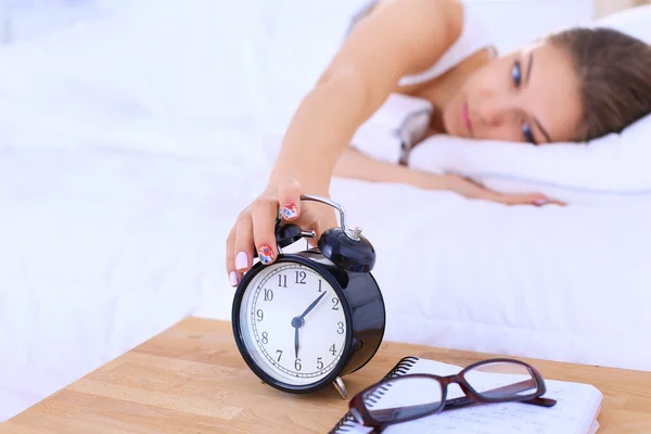 Une jeune femme éteint son réveil le matin — Photo