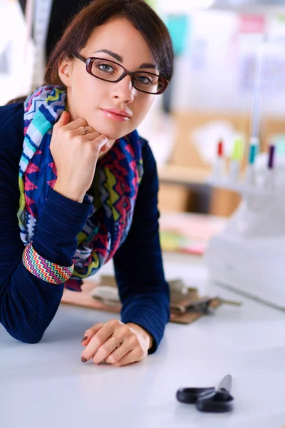 Bonito designer de moda sentado na mesa em estúdio — Fotografia de Stock