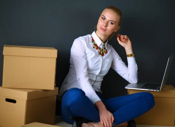 Woman sitting on the floor near a boxes with laptop — Stock Photo, Image