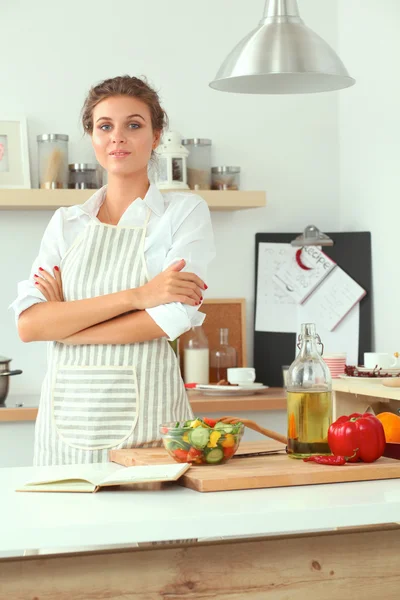 Smiling young woman standing in the kitchen — Stock Photo, Image