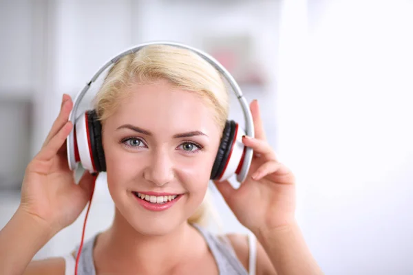 Young beautiful woman at home sitting on sofa and listening music — Stock Photo, Image