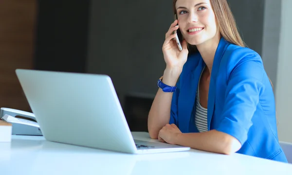 Portret van een jonge vrouw op telefoon achter een laptopcomputer — Stockfoto