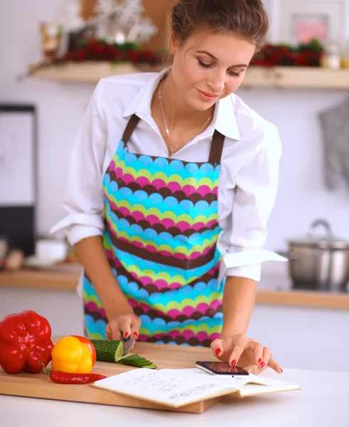 Glimlachende vrouw met haar mobiele telefoon in de keuken — Stockfoto