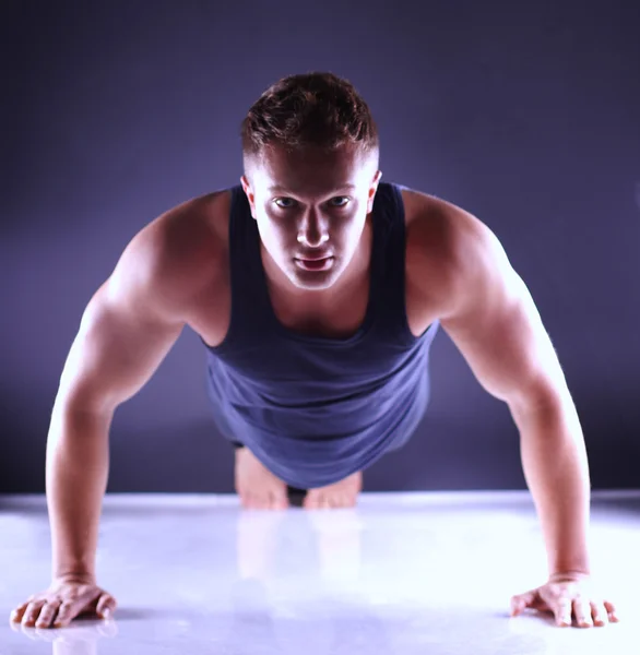 Hombre de fitness haciendo flexiones en el suelo, fondo gris aislado —  Fotos de Stock