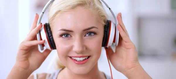 Young beautiful woman at home sitting on sofa and listening music — Stock Photo, Image