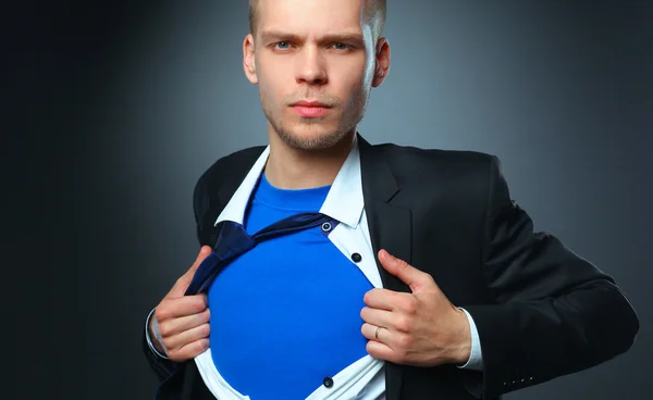 Молодий бізнесмен грає як супер герой і розриває сорочку, ізольовані на сірому фоні — стокове фото