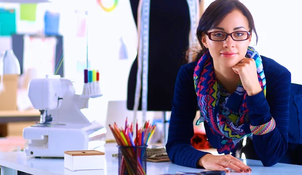 Beautiful fashion designer sitting at the desk in studio — Stock Photo, Image