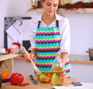 Masanın yanında duran taze salatayı karıştıran genç kadın.