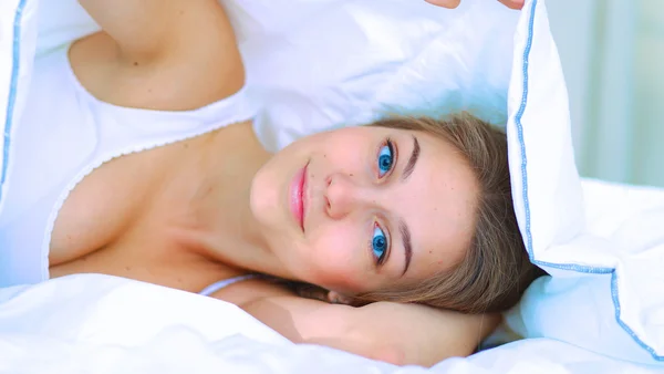 Νεαρή όμορφη γυναίκα ξαπλωμένη στο κρεβάτι καλυμμένη. — Φωτογραφία Αρχείου