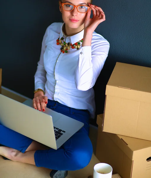 Žena sedící na podlaze u krabic s laptopem — Stock fotografie