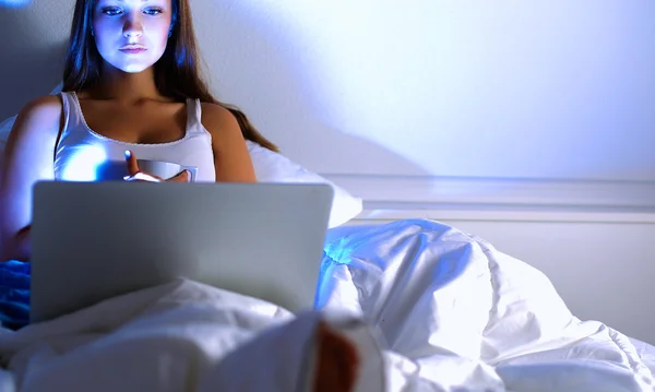 Femme souriante utilisant un ordinateur portable au lit — Photo