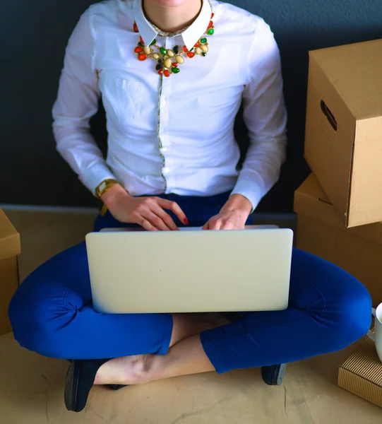 लॅपटॉप एक बॉक्स जवळ मजलावर बसलेली स्त्री — स्टॉक फोटो, इमेज