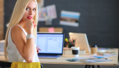 Moda tasarımcıları stüdyoda çalışıyor. Masanın üzerinde oturuyorlar.