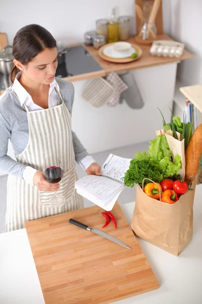 Mooie vrouw die thuis wat wijn drinkt in de keuken . — Stockfoto