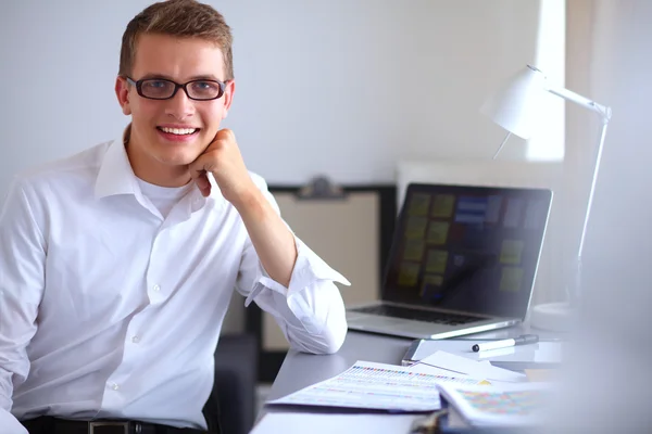 Молодой бизнесмен работает в офисе, сидит возле стола — стоковое фото