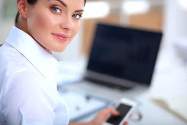 Aantrekkelijke zakenvrouw zit op het bureau in het kantoor — Stockfoto