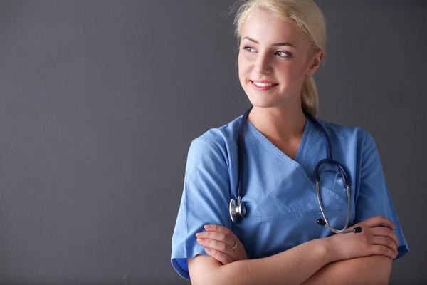 Молодая врач женщина со стетоскопом изолированы на сером фоне — стоковое фото