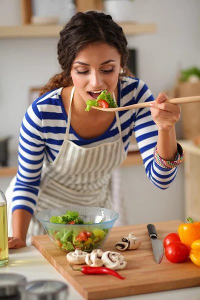 Genç kadın modern mutfakta taze salata yiyor. — Stok fotoğraf