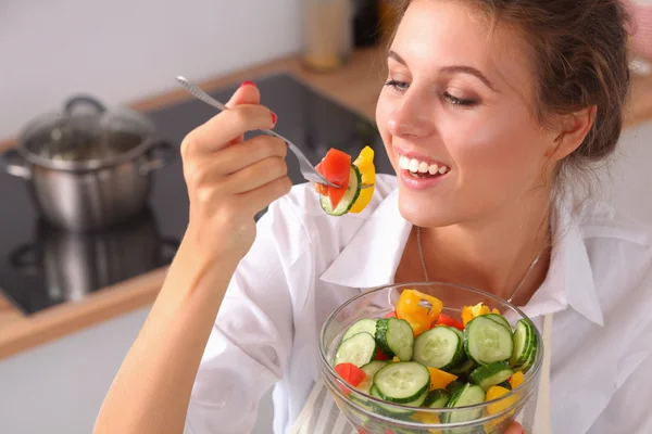 Mujer joven comiendo ensalada fresca en la cocina moderna — Foto de Stock