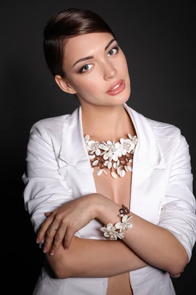 Portrait of young woman with beads, standing on gray background — Stock Photo, Image