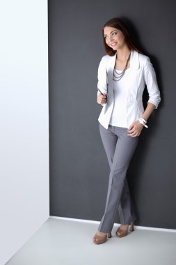 Bir dizüstü bilgisayar, gri arka plan üzerinde ayakta tutan genç kadın