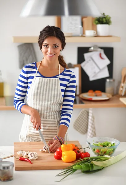 Jonge vrouw snijden groenten in de keuken — Stockfoto