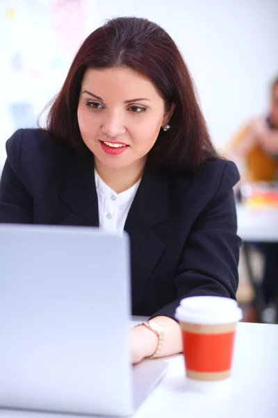 Attraktive Geschäftsfrau sitzt mit Tasse Kaffee am Schreibtisch im Büro — Stockfoto