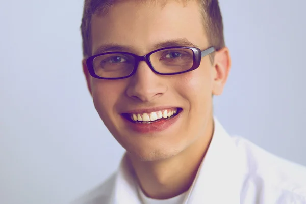 Retrato de un joven sonriendo sentado sobre un fondo gris —  Fotos de Stock