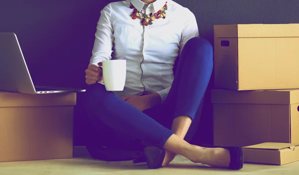 Femme assise sur le sol près d'une boîte avec ordinateur portable — Photo