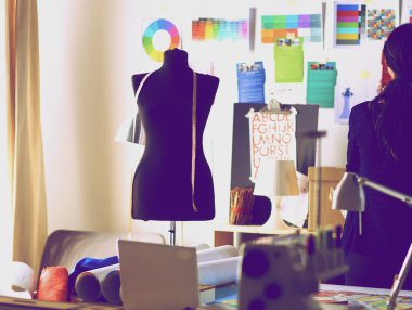 Güzel moda tasarımcısı stüdyoda duruyor.