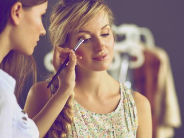 Kadından profesyonel makyaj yapan sanatçı.