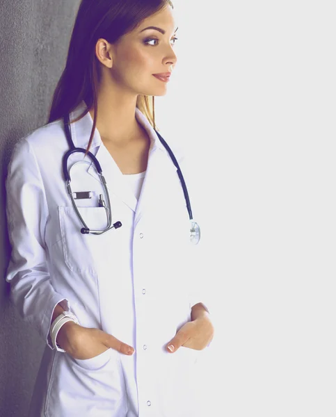 Mujer doctora con estetoscopio de pie sobre fondo gris — Foto de Stock