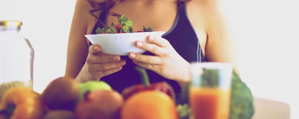 Девушка сидит на кухне на столе с фруктами — стоковое фото