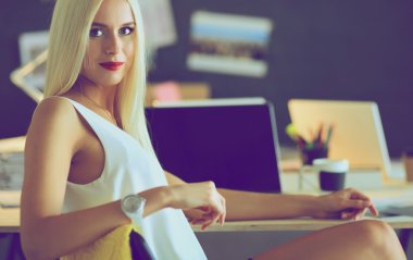 Moda tasarımcıları stüdyoda çalışıyor. Masanın üzerinde oturuyorlar.