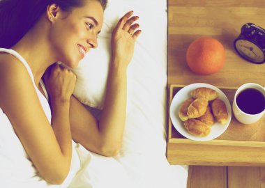 Genç ve güzel bir kadın yatakta yatıyor.