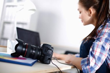 Masada dizüstü bilgisayarla oturan kadın fotoğrafçı.