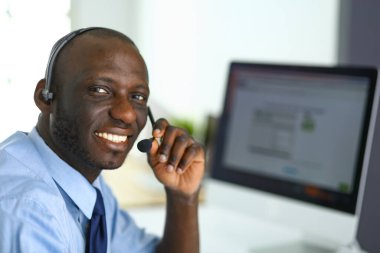 Kulaklıklı Afro-Amerikan işadamı laptopuyla çalışıyor.