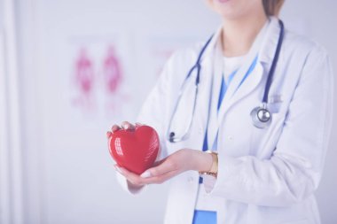 Steteskop tutan, kalbi hafif arka planda olan kadın bir doktor.