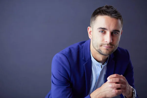 Joven empresario sentado aislado sobre fondo gris. —  Fotos de Stock