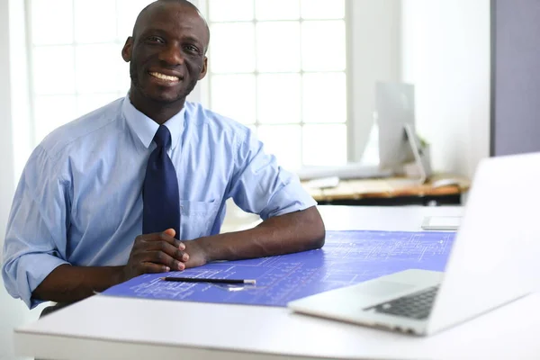 Afrikanischer Architekt arbeitet mit Computer und Bauplänen im Büro — Stockfoto