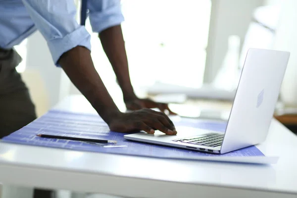 Afrykański architekt pracujący z komputerem i planami w biurze — Zdjęcie stockowe