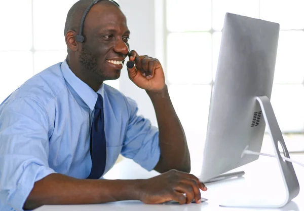 Afrikaans Amerikaans zakenman op headset werken op zijn laptop — Stockfoto