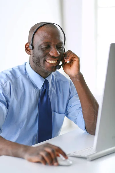 Afrikaans Amerikaans zakenman op headset werken op zijn laptop — Stockfoto