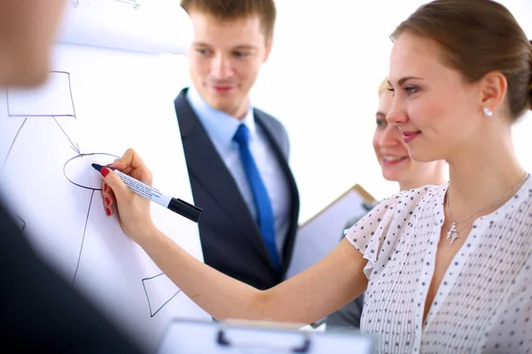 Businesswoman writing on flipchart while giving presentation to colleagues in office — Stock Photo, Image