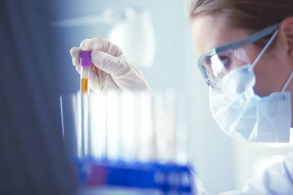 A medical or scientific researcher or doctor looking at a test tube of liquid green solution in a laboratory — Stock Photo, Image