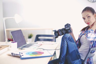 Masada dizüstü bilgisayarla oturan kadın fotoğrafçı.