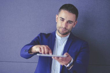 Gri arka planda yalnız oturan genç iş adamı.