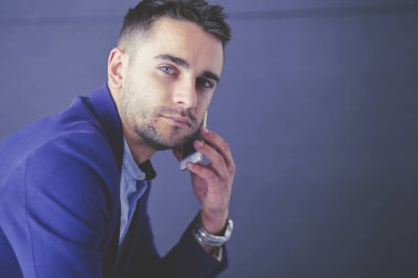 Gri arka planda yalnız oturan genç iş adamı.